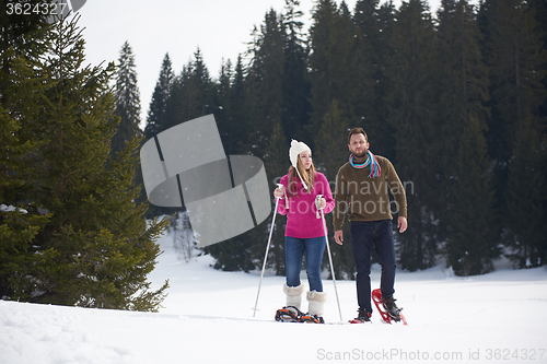 Image of couple having fun and walking in snow shoes