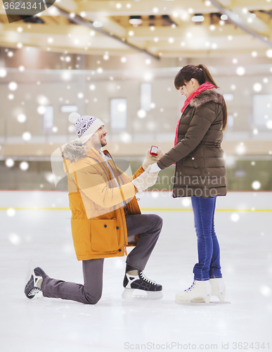 Image of happy couple with engagement ring on skating rink
