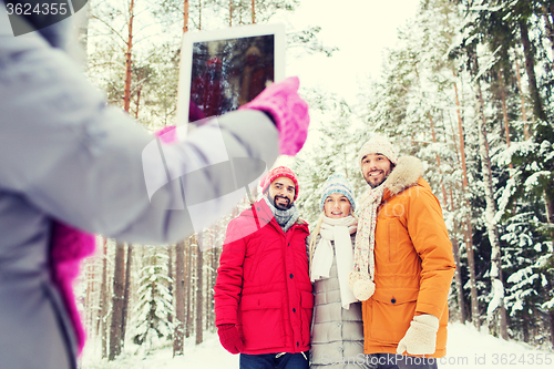 Image of smiling friends with tablet pc in winter forest