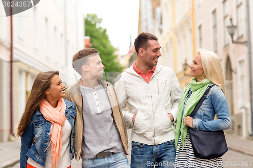 Image of group of smiling friends walking in the city