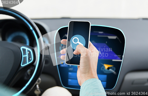 Image of close up of man hand with smartphone driving car