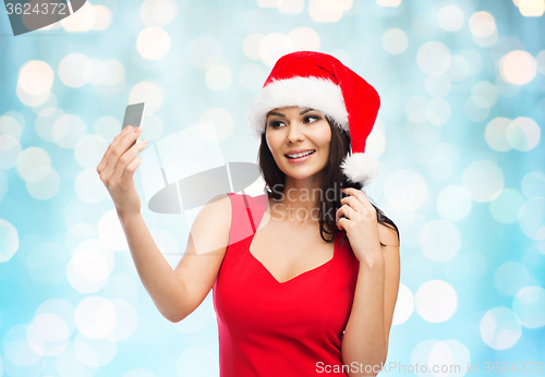 Image of woman in santa hat taking selfie by smartphone