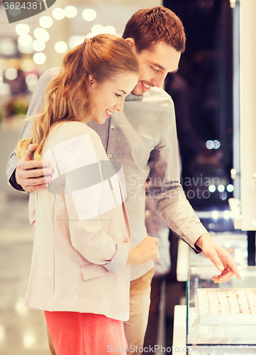 Image of happy couple choosing engagement ring in mall