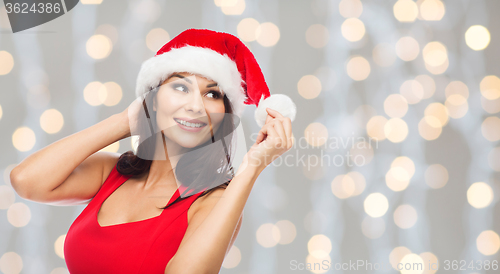 Image of beautiful woman in santa hat over christmas lights