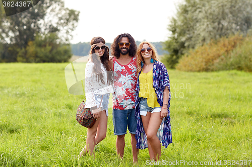 Image of smiling young hippie friends on green field