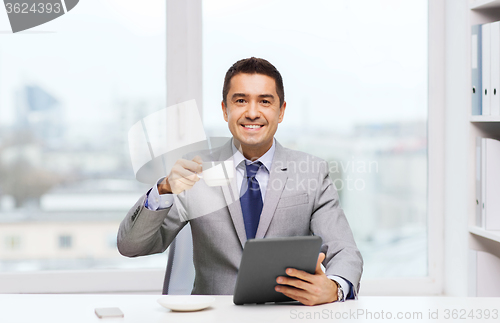 Image of smiling businessman with tablet pc and coffee cup