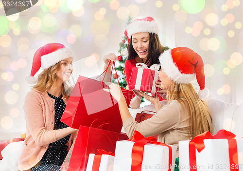 Image of happy women in santa hats with christmas gifts