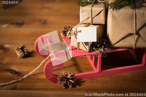 Image of close up of christmas gifts with note on sleigh
