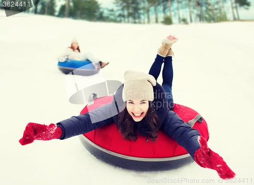 Image of group of happy friends sliding down on snow tubes