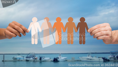 Image of hands holding people pictogram over boats in sea