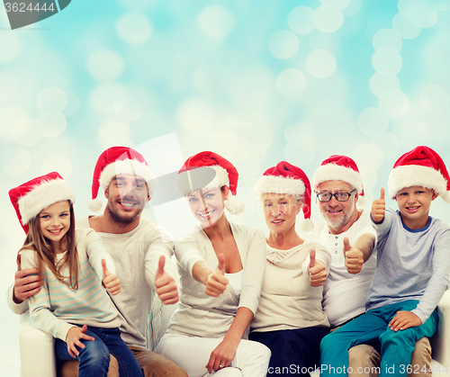 Image of happy family in santa hats showing thumbs up