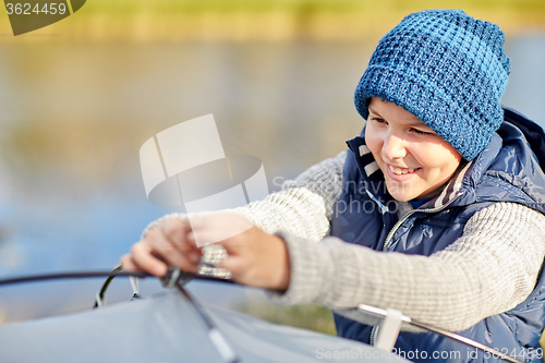 Image of happy boy setting up tent outdoors