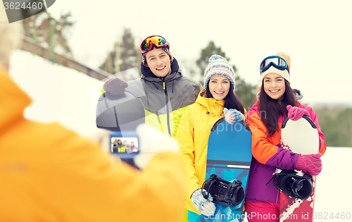 Image of happy friends with snowboards and smartphone