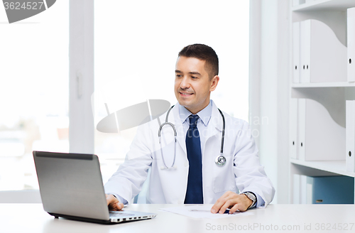 Image of smiling male doctor with laptop in medical office