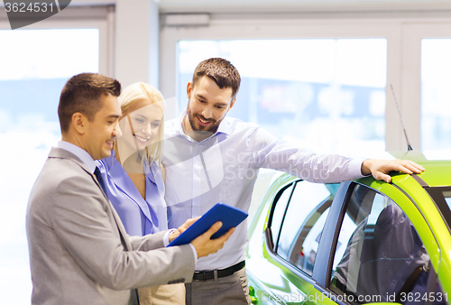 Image of happy couple with car dealer in auto show or salon