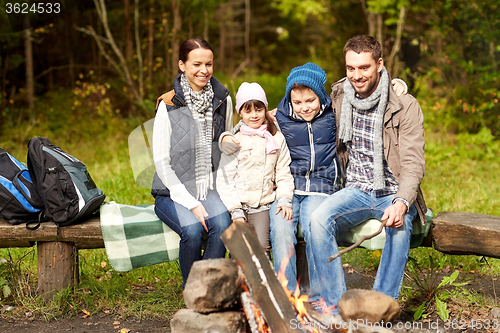 Image of happy family sitting on bench at camp fire