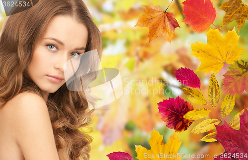 Image of beautiful young woman face over autumn leaves