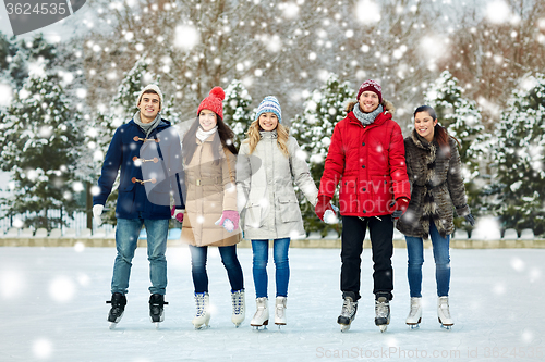 Image of happy friends ice skating on rink outdoors