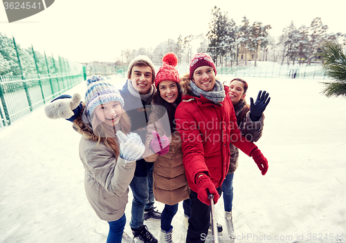 Image of happy friends with smartphone on ice skating rink