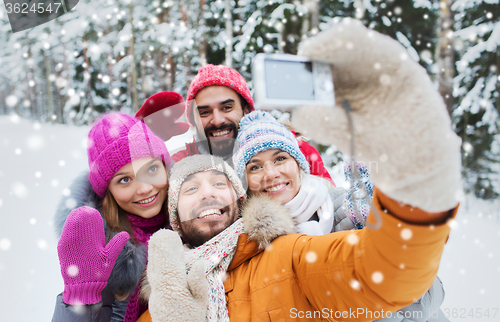 Image of smiling friends with camera in winter forest