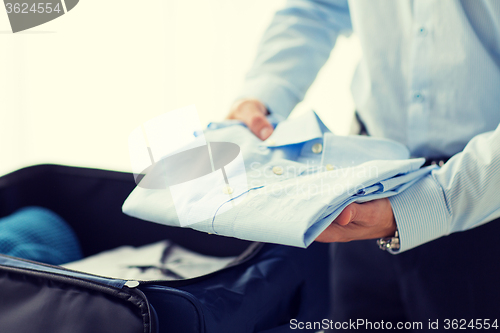 Image of businessman packing clothes into travel bag