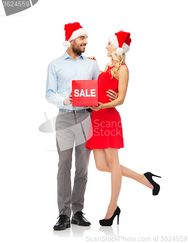 Image of happy couple in santa hats with red sale sign