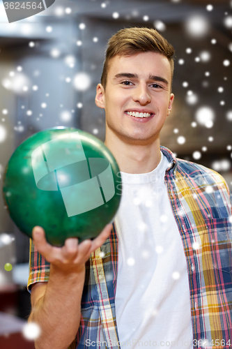 Image of happy young man holding ball in bowling club