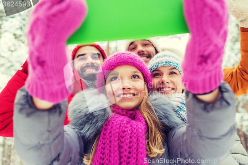 Image of smiling friends with tablet pc in winter forest