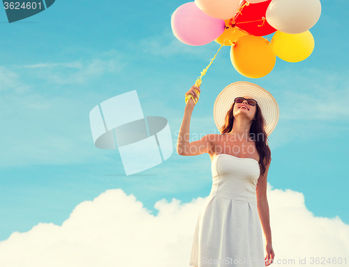 Image of smiling young woman in sunglasses with balloons