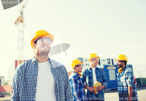 Image of group of smiling builders in hardhats outdoors