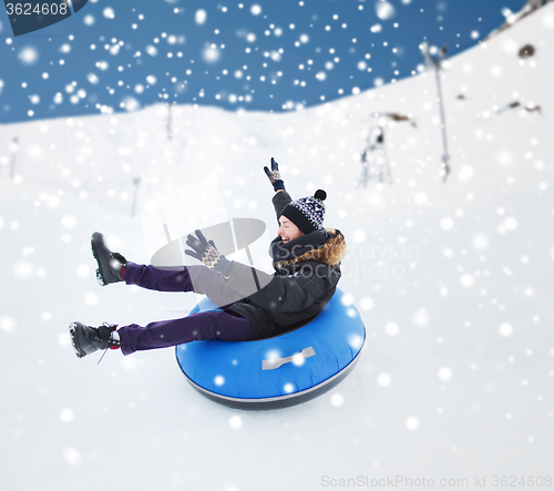 Image of happy young man sliding down on snow tube