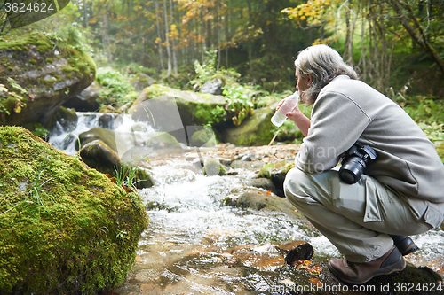 Image of man drinking fresh water from spring