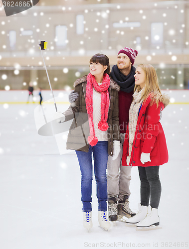 Image of happy friends with smartphone on skating rink