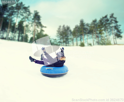 Image of happy young man sliding down on snow tube