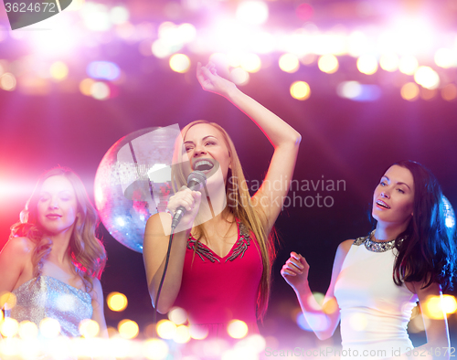 Image of happy women singing karaoke and dancing