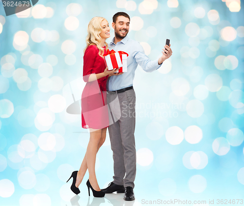 Image of happy couple with smartphone and gift boxes