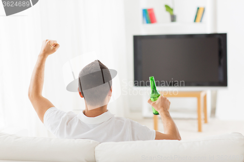 Image of man watching tv and drinking beer at home