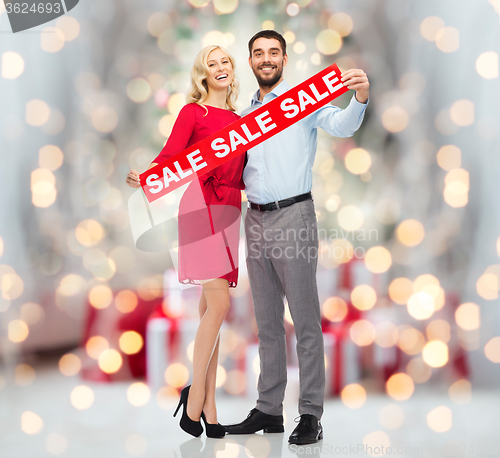 Image of happy couple with sale sign over christmas lights