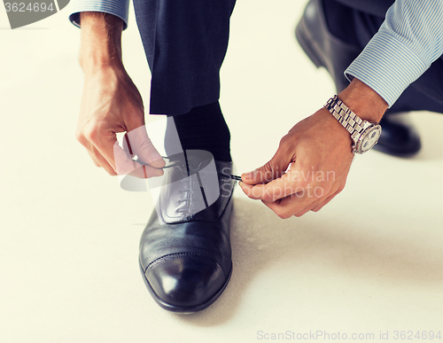 Image of close up of man leg and hands tying shoe laces