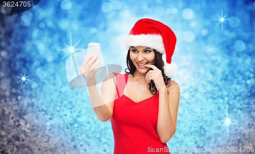 Image of woman in santa hat taking selfie by smartphone