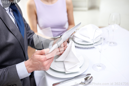 Image of close up of couple with tablet pc at restaurant