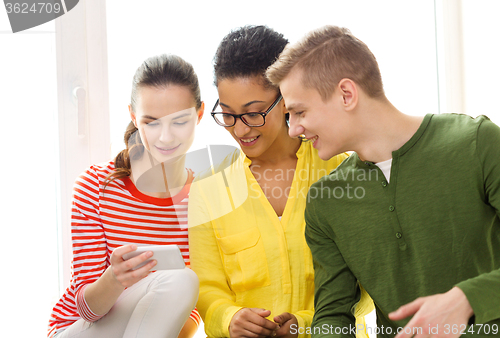 Image of three smiling students with smartphone at school