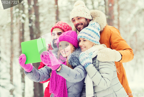 Image of smiling friends with tablet pc in winter forest