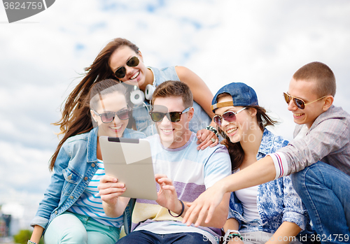 Image of group of smiling teenagers looking at tablet pc