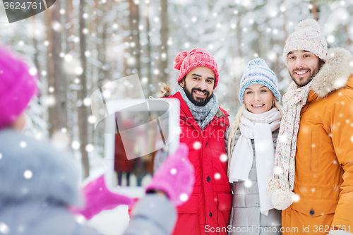 Image of smiling friends with tablet pc in winter forest