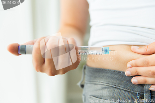 Image of close up of hands making injection by insulin pen