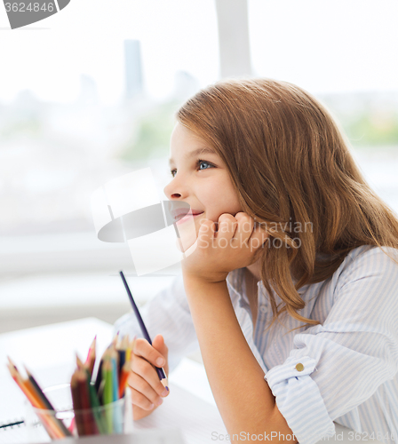 Image of little student girl drawing and dreaming at school
