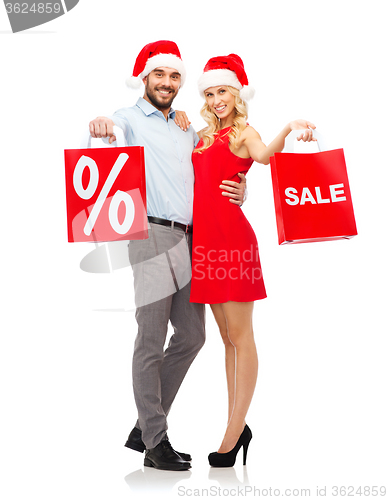 Image of happy couple in santa hats with red shopping bags