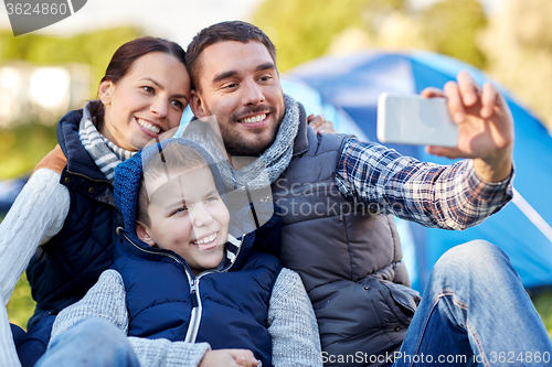 Image of family with smartphone taking selfie at campsite