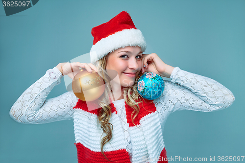 Image of Girl dressed in santa hat holding a Christmas decoration  